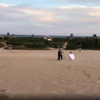 Vídeo Pílulas – Noivos e fotógrafo caminham na areia.