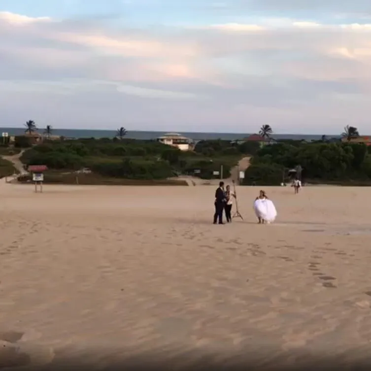 Vídeo Pílulas – Noivos e fotógrafo caminham na areia.